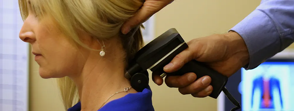 Chiropractor using tool on woman's neck