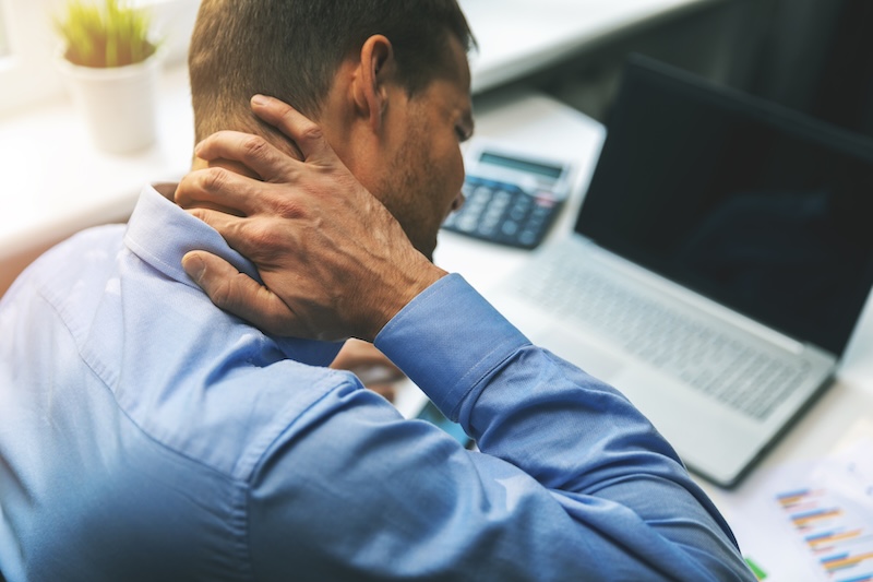 office syndrome - man suffering from neck and back pain while working with computer