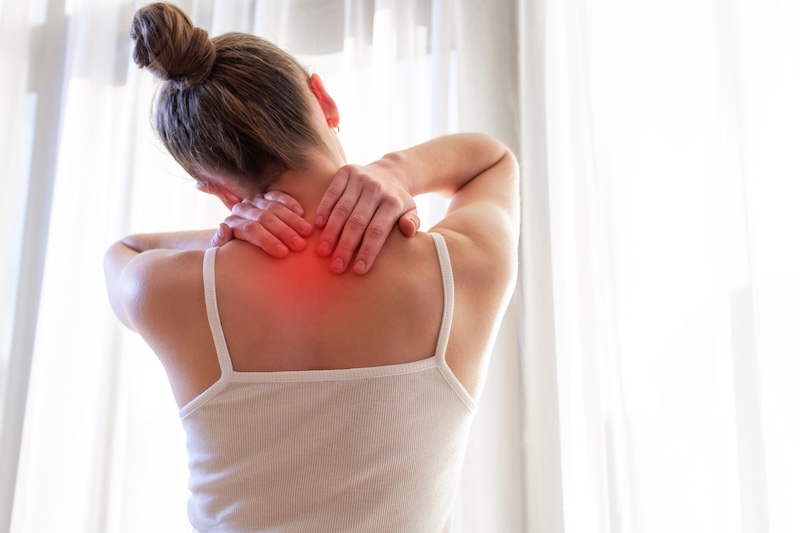 Young woman massaging her neck because of suffering from pain neck, stretching the muscles.